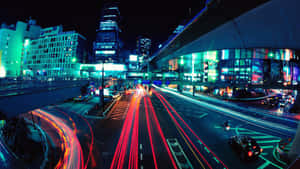 夜間城市，有汽車光跡和發光的霓虹燈招牌。