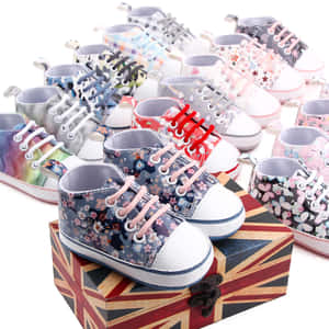 色彩繽紛的嬰兒運動鞋，帶有花卉圖案，排列在 Union Jack 盒子上。 — 卡通鞋 壁紙