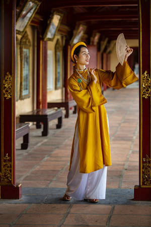 身穿傳統黃色服飾的女性在寺廟走廊中拿著扇子 — 亞洲 壁紙