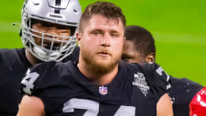 NFL美式足球員在綠色球場上比賽時穿著Raiders制服。