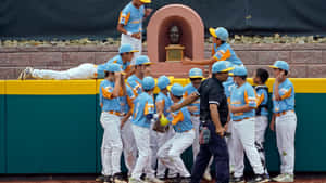年輕棒球隊在休息區附近與教練慶祝勝利。 — 2560x1440 壁紙