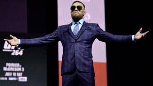 Conor McGregor 身穿紫色格紋西裝和太陽眼鏡在UFC舞台上擺姿勢。 — 康納·麥格雷戈 壁紙