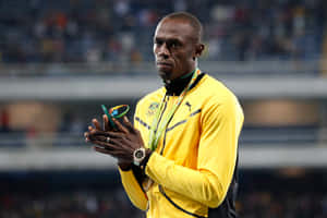 Usain Bolt 身穿黃色牙買加運動服，手持銅牌鼓掌。