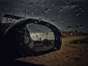 濺滿雨水的車窗，顯示側鏡反射出黃昏時分荒涼的路邊。