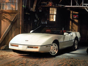 白色Corvette開篷車在木車庫中，陽光照射進來。
