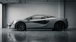 銀色McLaren跑車停放在具有反射地面的極簡工業車庫中。