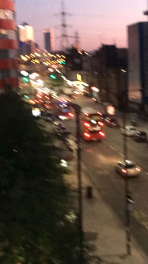 黃昏時模糊的城市街景，有移動的汽車和明亮的燈光。