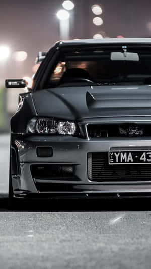 黑色日產Skyline R34在夜晚停泊在城市的街燈下。