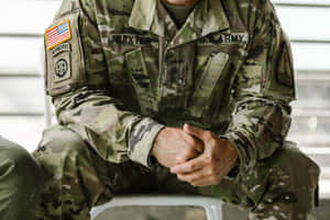 一名身穿迷彩制服的美國陸軍士兵雙手合十坐著。 — 軍事動圖 壁紙