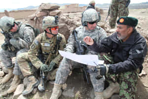 軍事人員與當地軍官在岩石沙漠環境中審閱地圖。 — 軍事動圖 壁紙