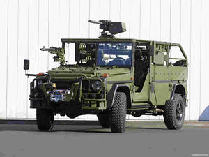 橄欖綠軍用吉普車配備武器，停放在白色牆前。 — 汽車 壁紙