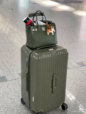 橄欖綠色行李箱及相配手提包放在機場地板上。 — 旅行 壁紙