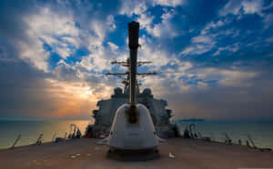 日落時分海洋上嘅軍艦炮塔同戲劇性雲朵 — 美國 壁紙