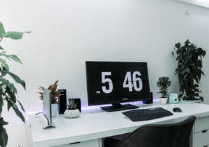 乾淨的現代書桌，帶有顯示5:46 PM的電腦時鐘和盆栽植物。