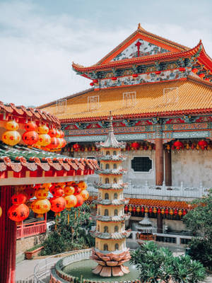 色彩繽紛的中國寺廟庭院，有紅色燈籠和中央的寶塔噴泉。