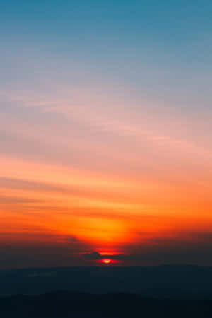 日落時分，山巒之上，天空呈現橙色和粉紅色