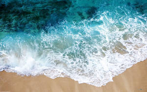 碧綠海浪沖刷金色沙灘，帶有白色泡沫。