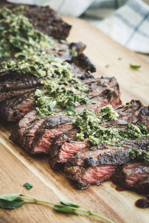 切片燒烤牛排配上香草醬，置於木製砧板上。 — 美食 壁紙