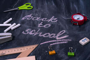 學校用品排列在黑板上，並用粉筆寫著「back to school」。