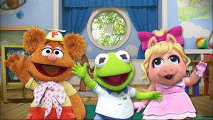三個 Muppet 角色喺色彩繽紛嘅兒童遊戲室入面揮手。 — 布公仔大電影 GIF 壁紙
