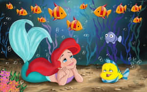 美人魚艾莉爾在海床上休息時與她的黃色魚朋友微笑。