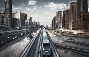 一列現代火車在黃昏時分行駛在高架軌道上，穿過密集的城市景觀。