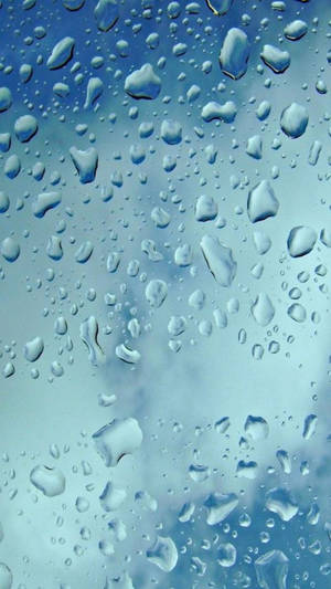 玻璃上雨滴的特寫，顯示藍天和白雲