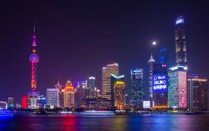 夜晚的上海天際線，閃爍的摩天大樓和倒映在河中的東方明珠塔。 — 唐人街 GIF 壁紙