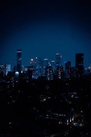 夜晚的城市景觀，有明亮的摩天大樓和下方的黑暗剪影。 — 夜晚 GIF 壁紙