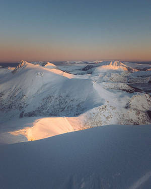 夕陽下積雪山脈，山峰金色光芒，天空清澈 — 日產 Skyline GTR R33 壁紙