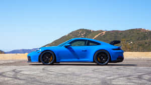 藍色保時捷911 GT3 RS在沙漠賽道上，帶有輪胎痕跡和山脈背景。