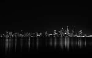 夜晚黑白城市天際線，建築燈光倒映在水中。 — 天際線 壁紙
