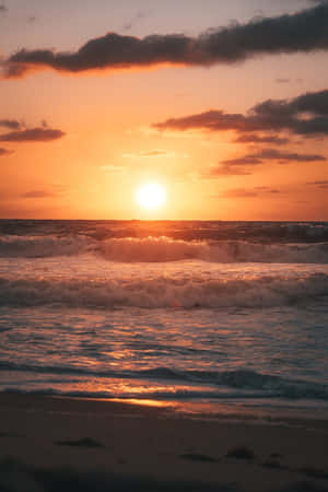夕陽下的海洋，波浪拍打沙灘，橙色和紫色的天空 — 海灘日落 壁紙