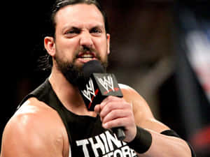 摔角手穿著黑色背心對著 WWE 麥克風大喊。 — 摔角 GIF 壁紙