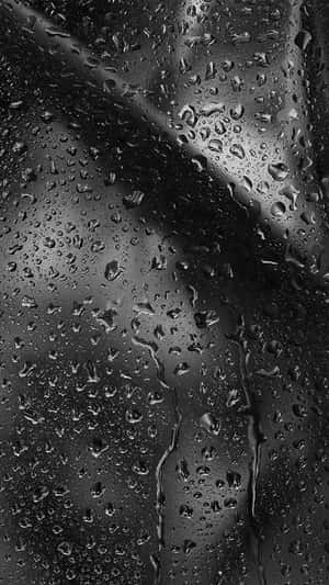 夜晚雨滴沿深色玻璃窗滑落