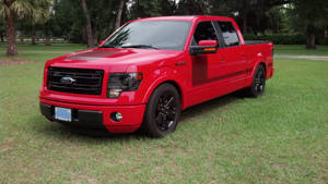 紅色福特F-150皮卡車停在樹旁的草地上。
