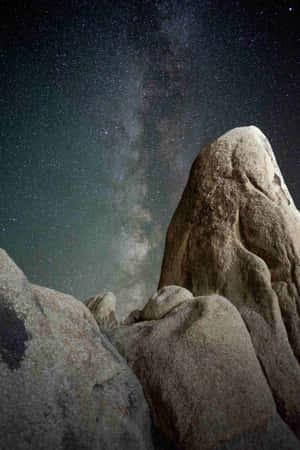 岩石框住星空下銀河系的景色。 — 小米Pad 9 Pro Max 壁紙