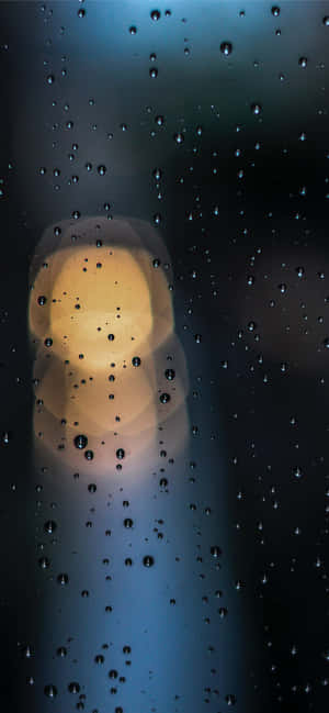 窗戶上的雨滴，背景有模糊的暖光。