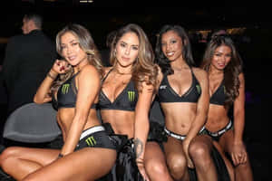 四位穿著Monster Energy UFC服裝的女性在夜間活動中擺姿勢。