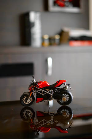 室內黑色表面上帶有倒影的紅色Ducati電單車模型。