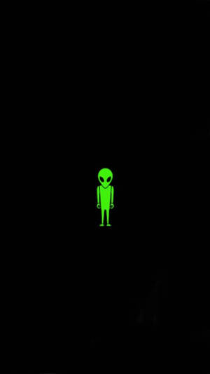 一個發光的綠色外星人剪影站在黑暗中。