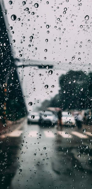 車窗上的雨滴，後面模糊的街道和汽車可見。