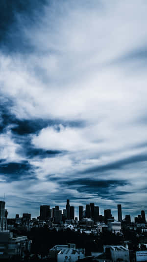 戲劇性的藍色多雲天空籠罩著黑暗的城市天際線。