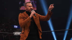 AEW 賽事中，摔角手在藍光下於擂台內對著麥克風說話。