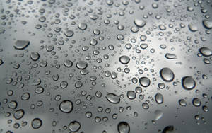 玻璃上的雨滴，背景為模糊的灰色天空