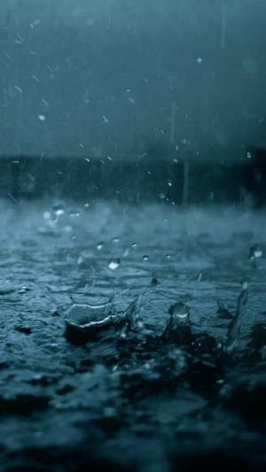暴風雨天氣下，雨滴在黑暗水面上濺起的特寫。