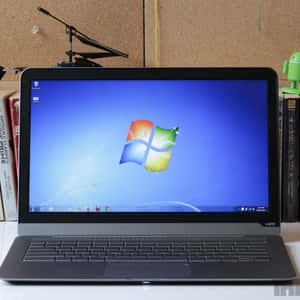 黑色手提電腦顯示Windows 7桌面，附近有書本和Android公仔。