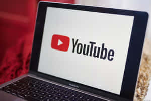 MacBook Pro 屏幕上顯示 YouTube 標誌，周圍為紅色和米色。 — YouTube 壁紙
