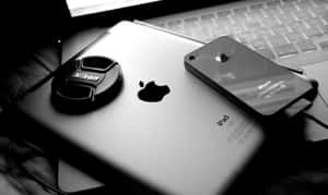 桌上科技產品的黑白照片，包括iPad、iPhone和手提電腦。