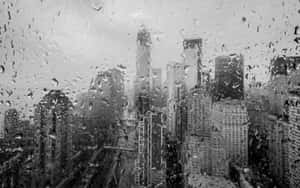雨滴模糊了透過窗戶看到的灰色調高聳城市建築。 — 天氣 壁紙